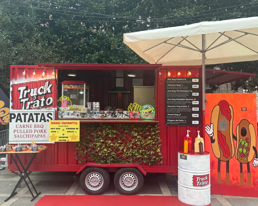 Food truck Truck o Trato con menú de hot dogs, patatas y fingers de pollo en un evento.